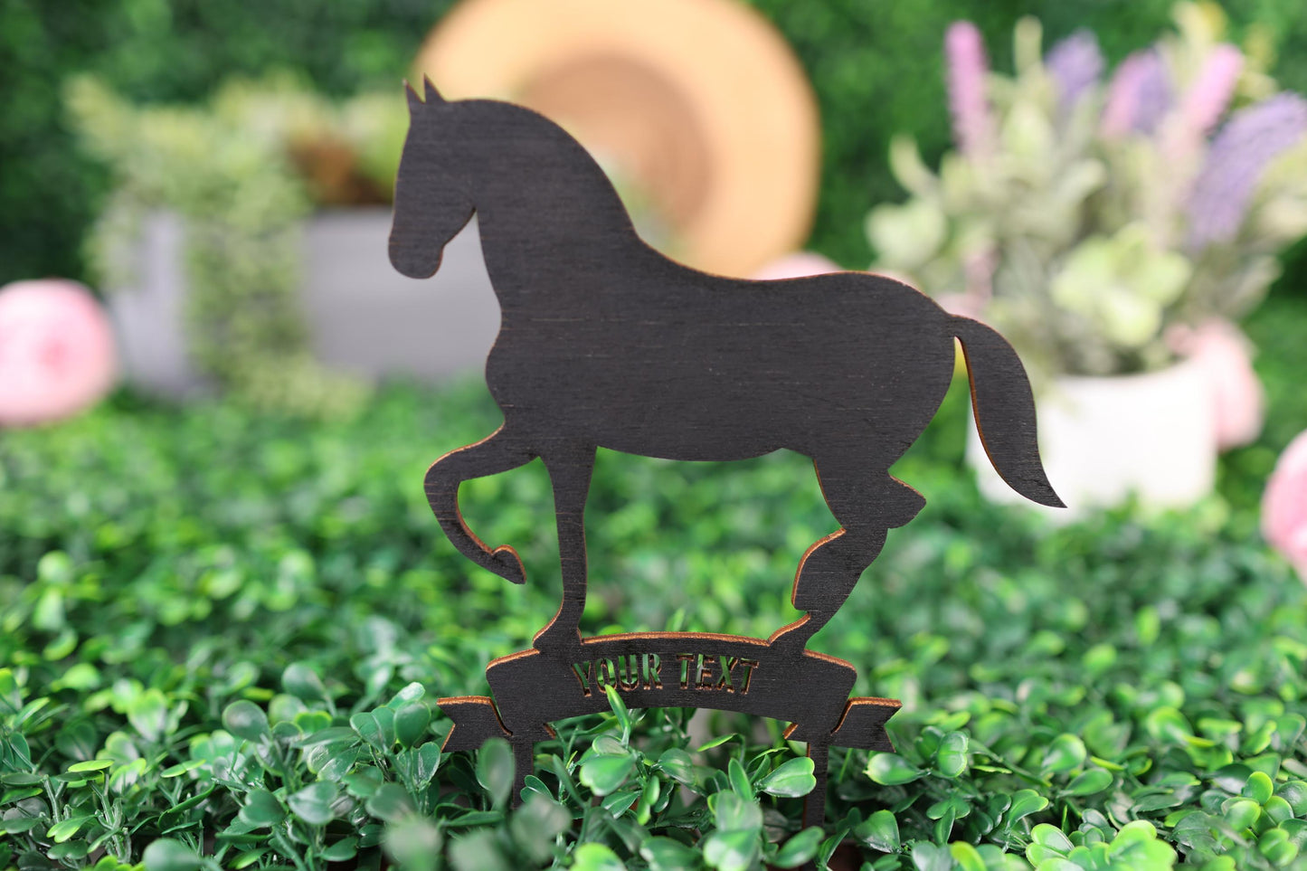a wooden horse standing on top of a lush green field