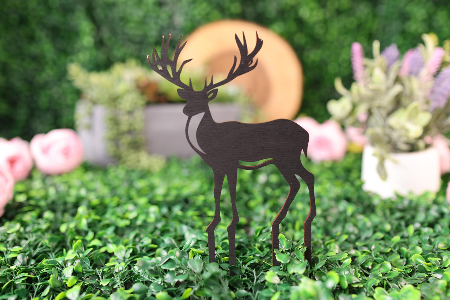 a deer cut out of wood standing in a field of flowers