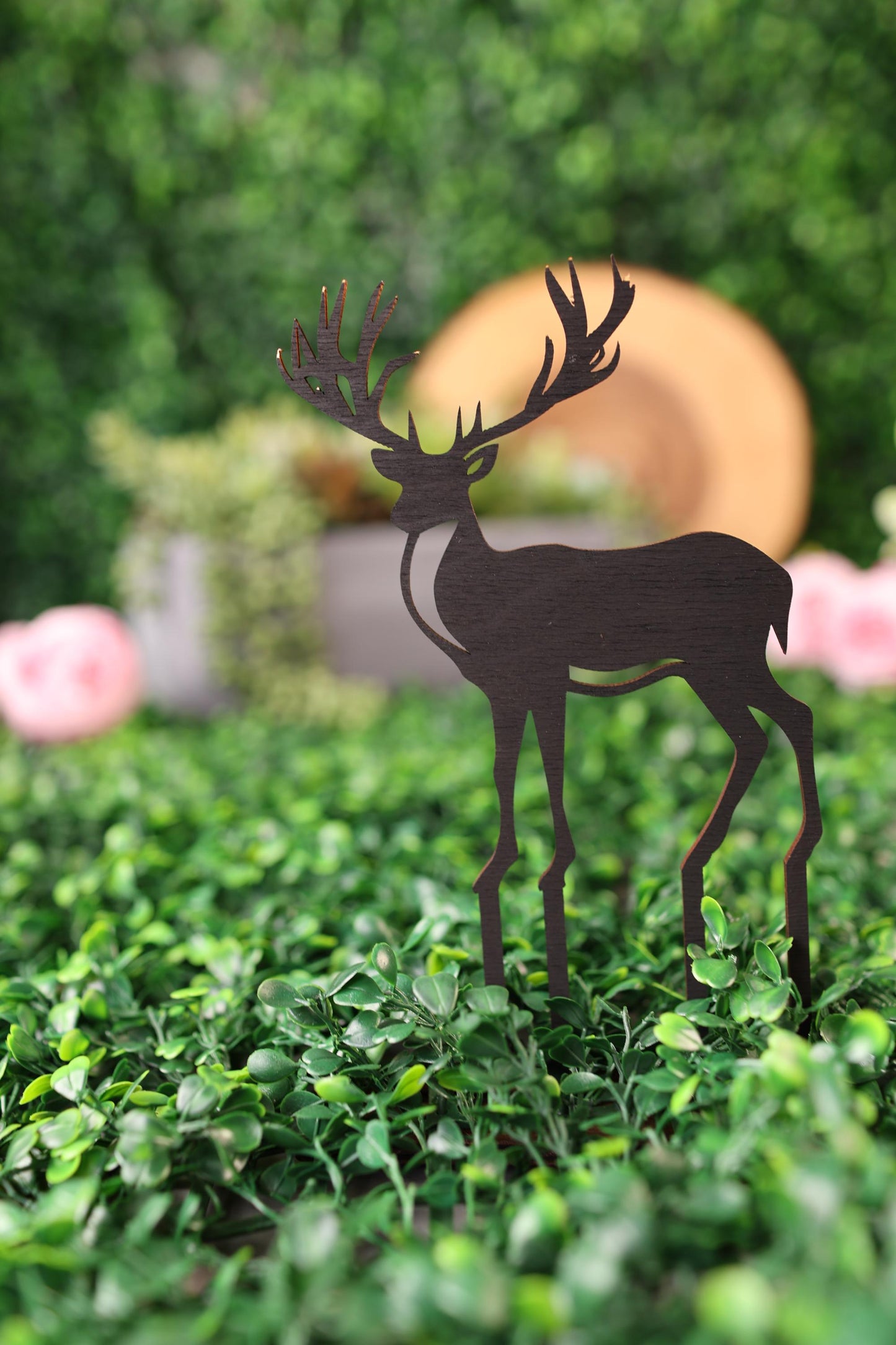 a paper cut out of a deer on top of a hedge
