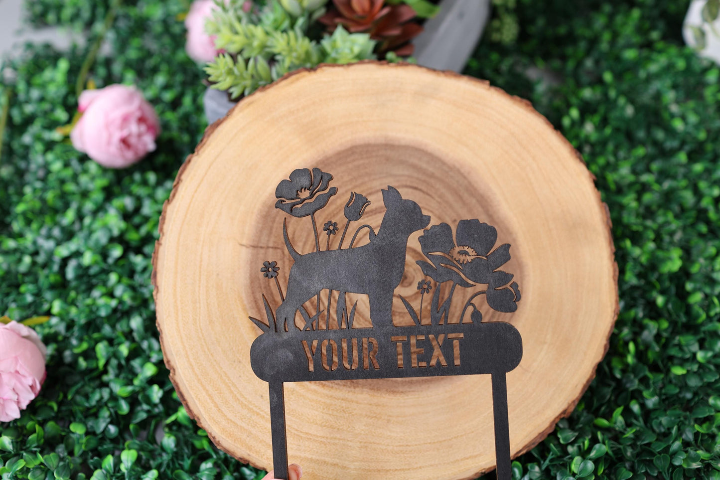 a hand holding a wooden sign with a dog on it