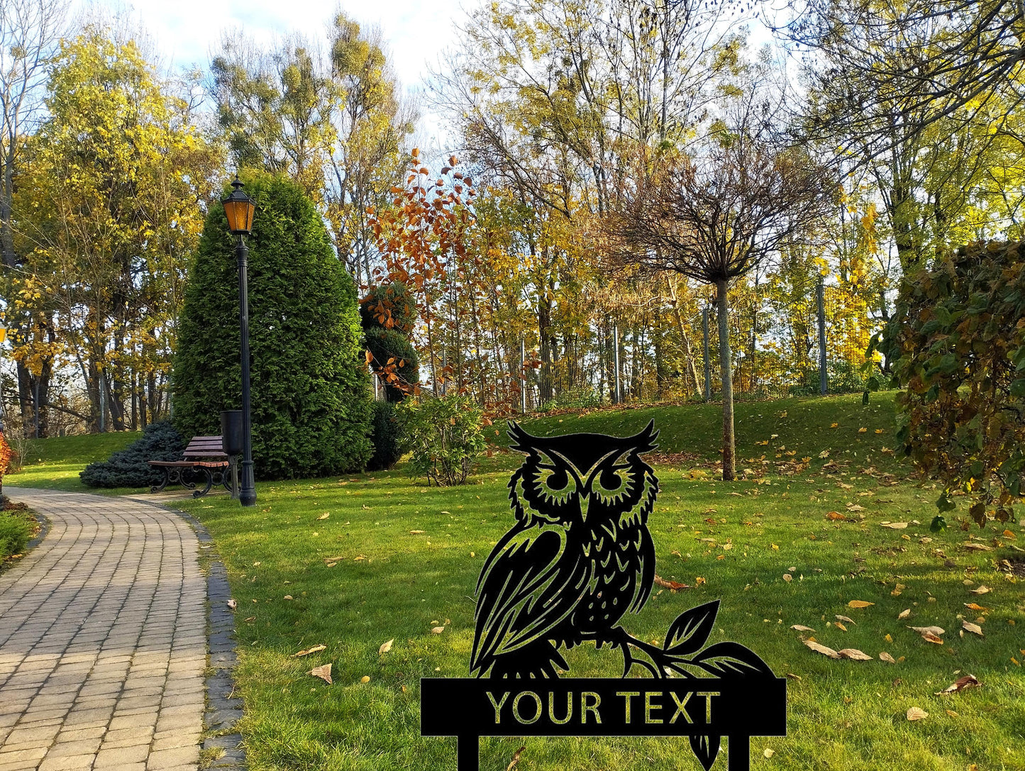 an owl sitting on top of a sign in a park