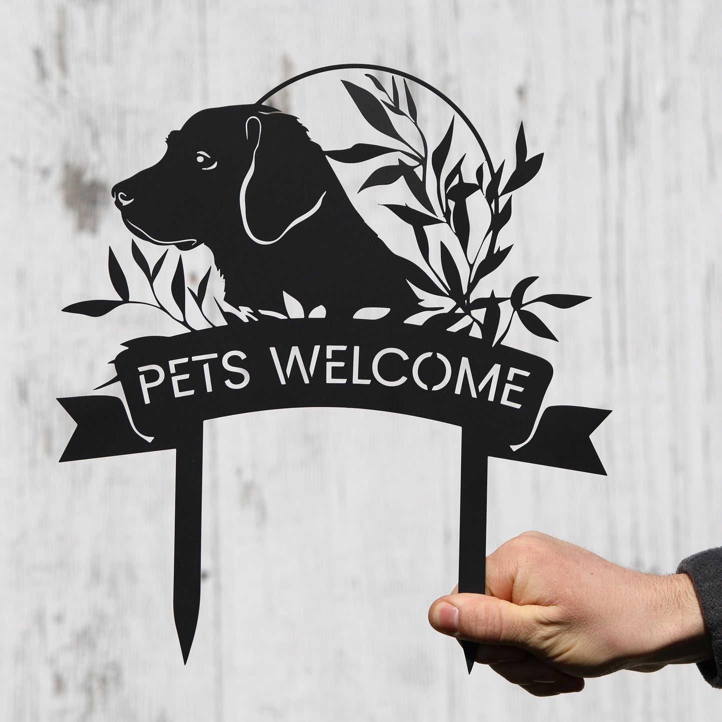 a hand holding a welcome sign with a dog on it