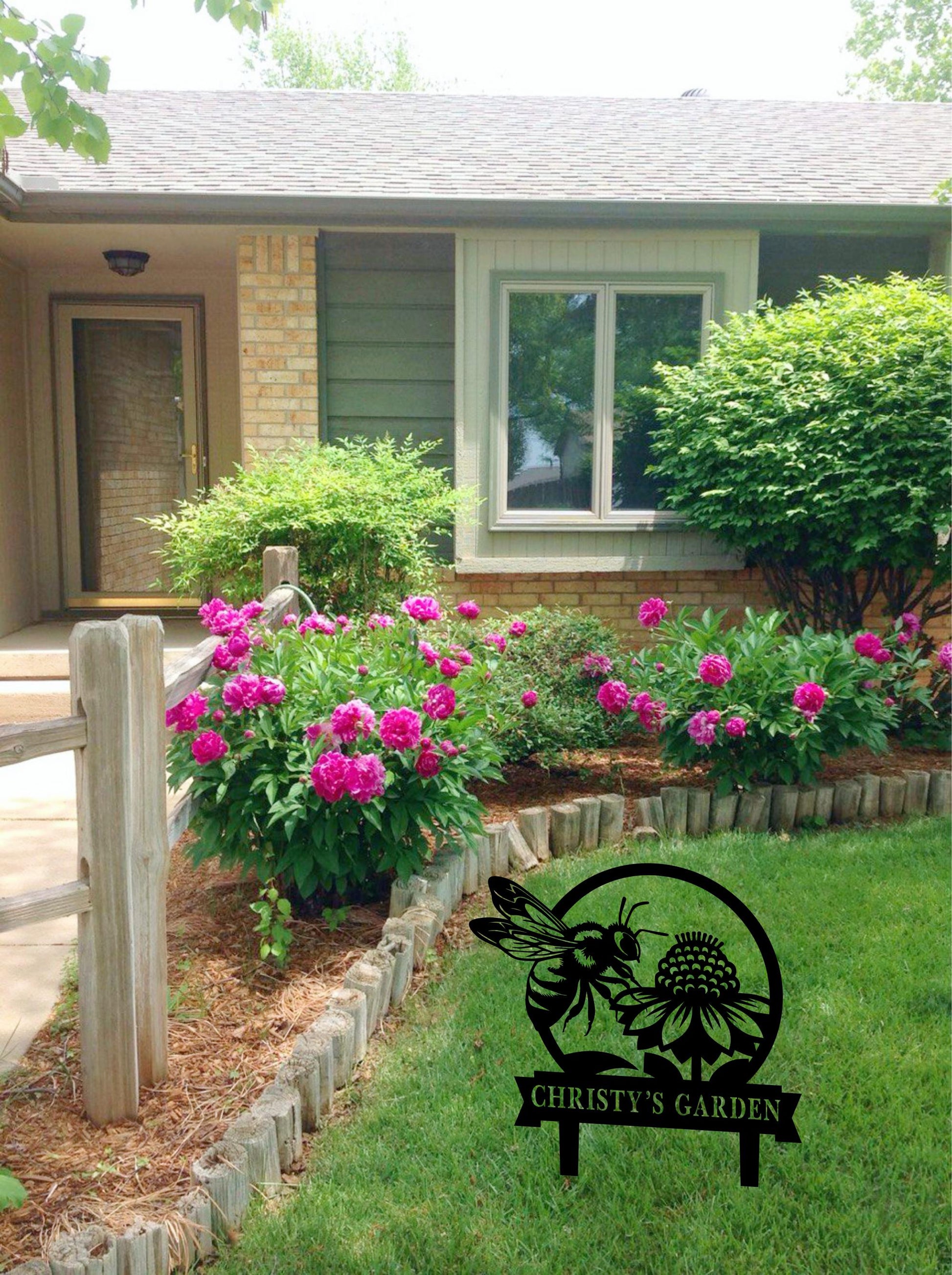 a garden with pink flowers in front of a house